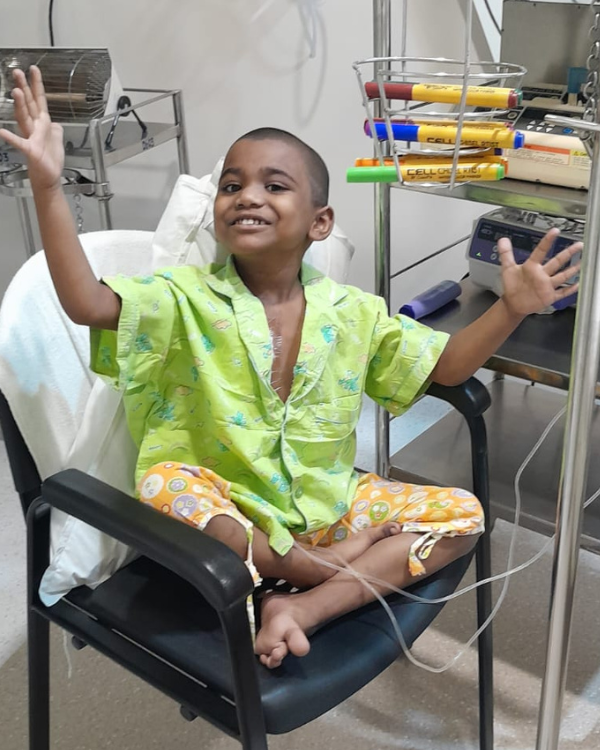 Keerthi with arms wide open and smiling in hospital